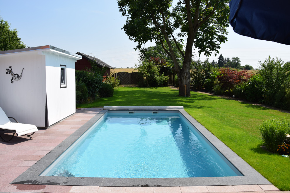 Imagen de piscina tradicional de tamaño medio rectangular en patio lateral con adoquines de piedra natural