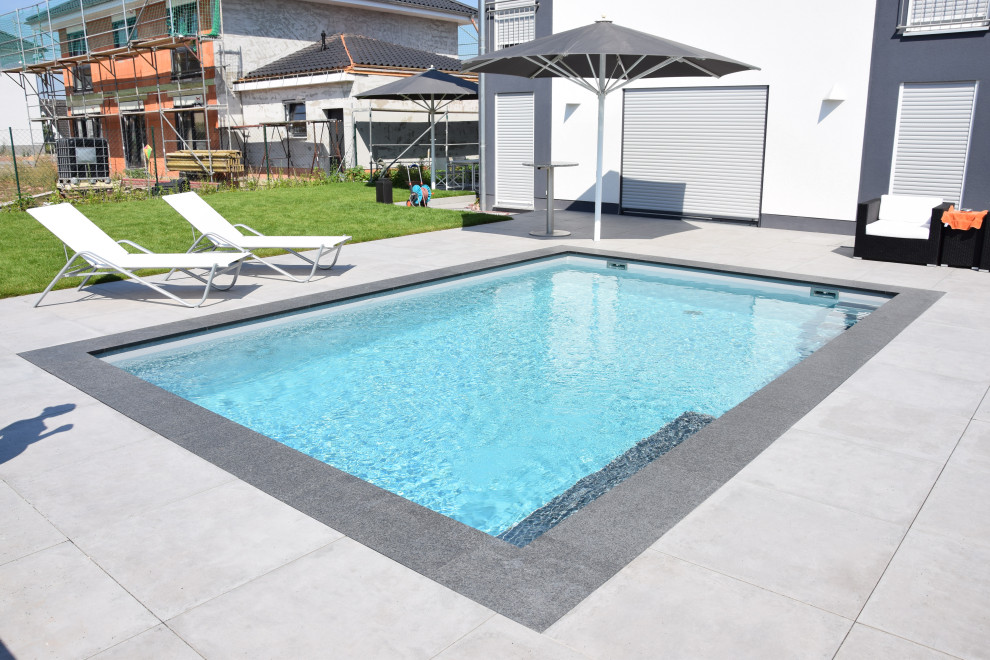 На фото: прямоугольный бассейн среднего размера на боковом дворе в современном стиле с покрытием из каменной брусчатки с