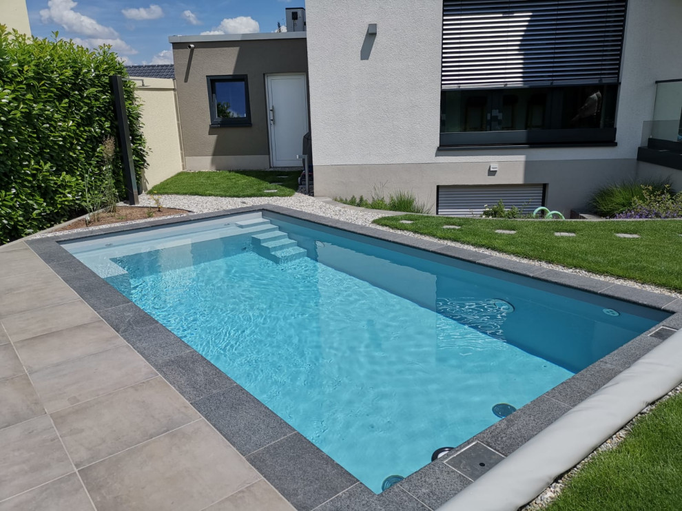 Стильный дизайн: прямоугольный бассейн среднего размера на боковом дворе в стиле модернизм с покрытием из каменной брусчатки - последний тренд