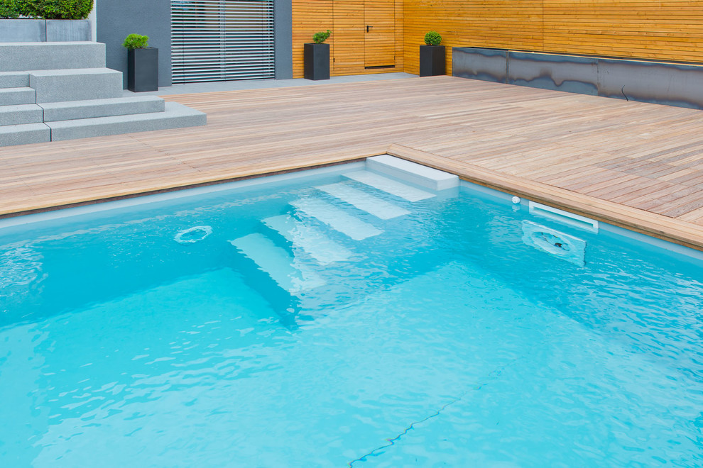 Réalisation d'une piscine hors-sol design de taille moyenne et rectangle avec une terrasse en bois.