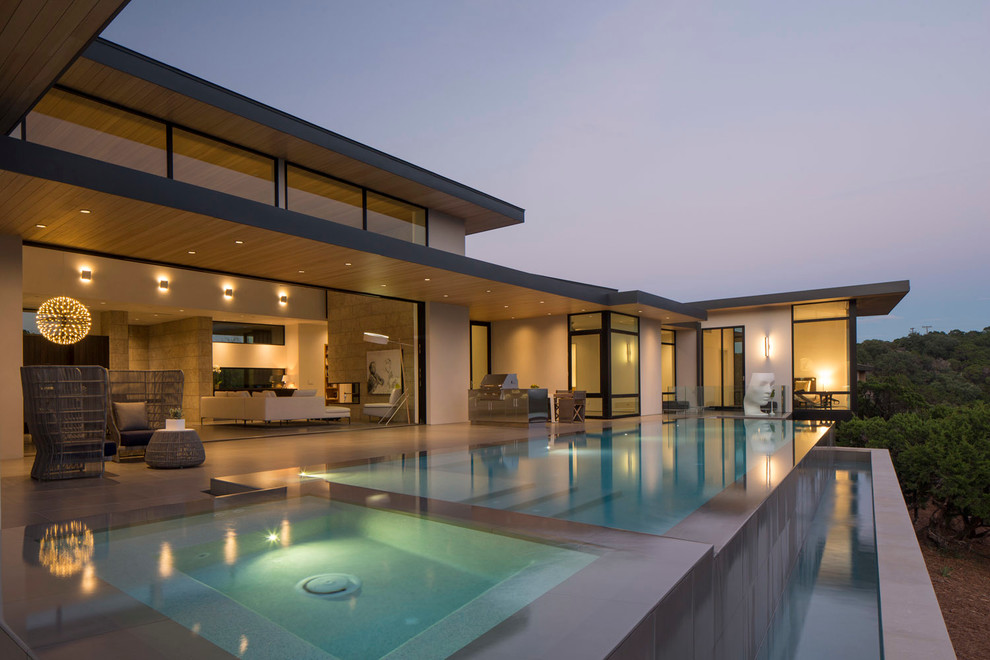 Идея дизайна: огромный прямоугольный бассейн-инфинити на заднем дворе в современном стиле с джакузи и покрытием из плитки