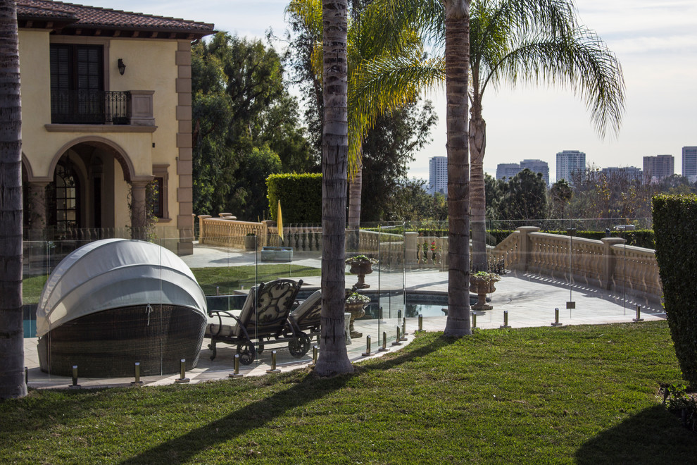 На фото: большой бассейн произвольной формы на заднем дворе в средиземноморском стиле с джакузи и мощением тротуарной плиткой