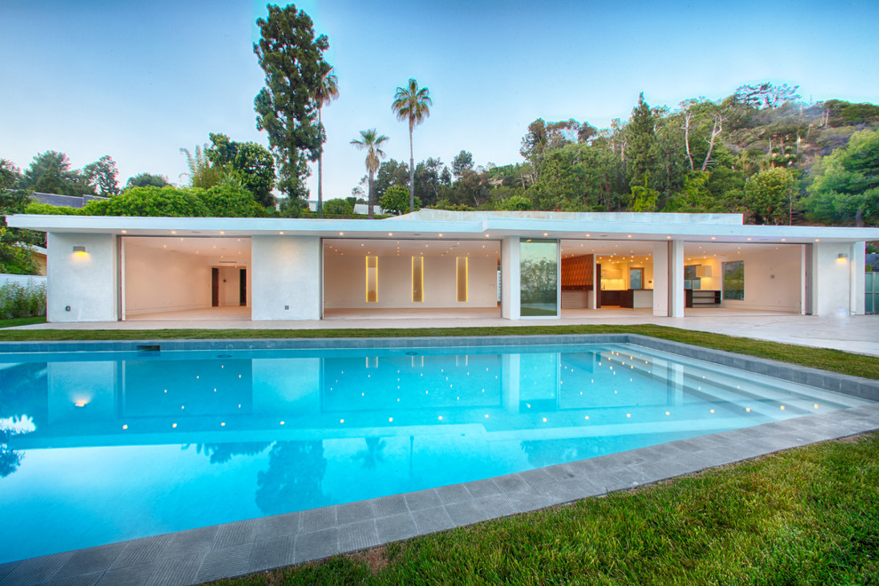 Esempio di una grande piscina naturale moderna personalizzata dietro casa con una vasca idromassaggio e cemento stampato