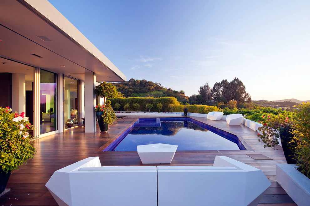 Example of a minimalist custom-shaped pool design in Los Angeles with decking