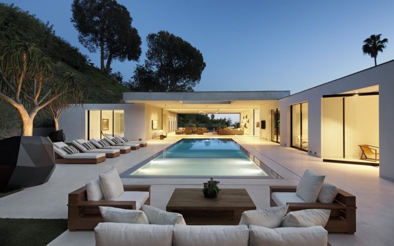 Ejemplo de piscina infinita moderna grande rectangular en patio trasero con adoquines de hormigón