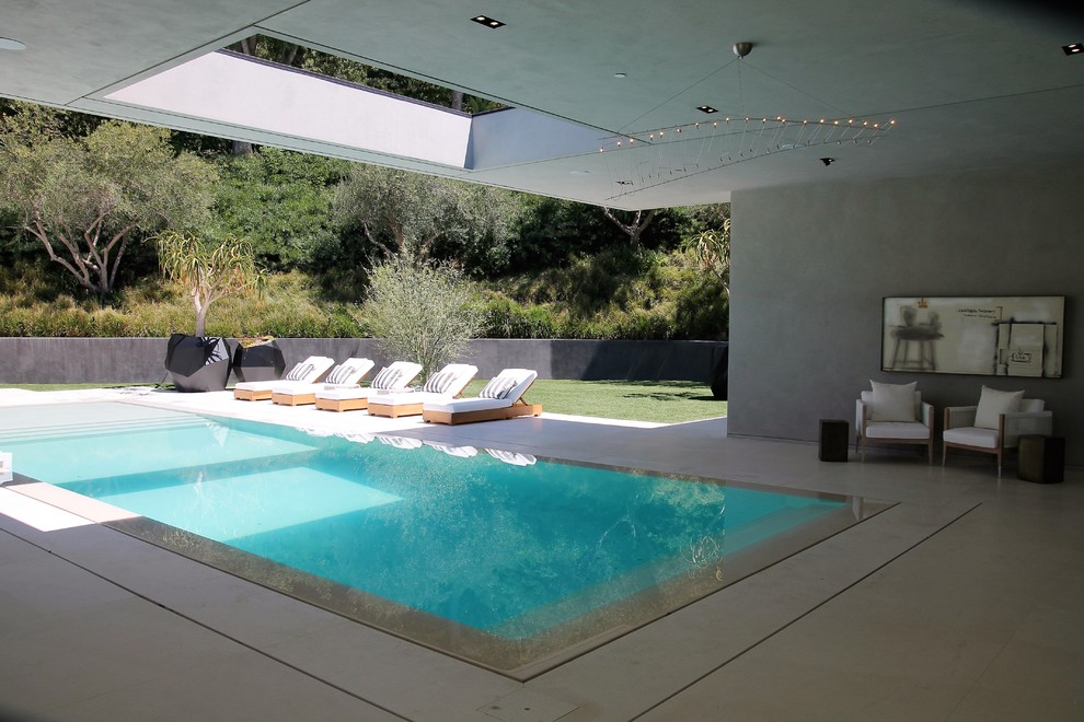 Idées déco pour une grande piscine à débordement et arrière moderne rectangle avec des pavés en béton.