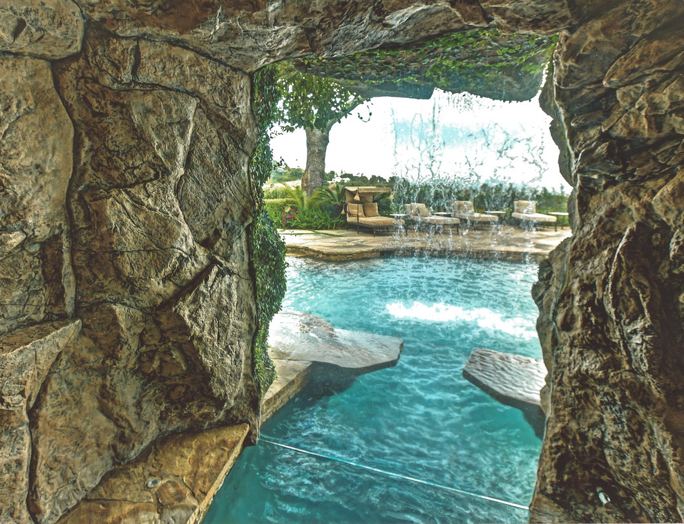 Immagine di un'ampia piscina naturale tropicale personalizzata dietro casa con pavimentazioni in pietra naturale e una vasca idromassaggio