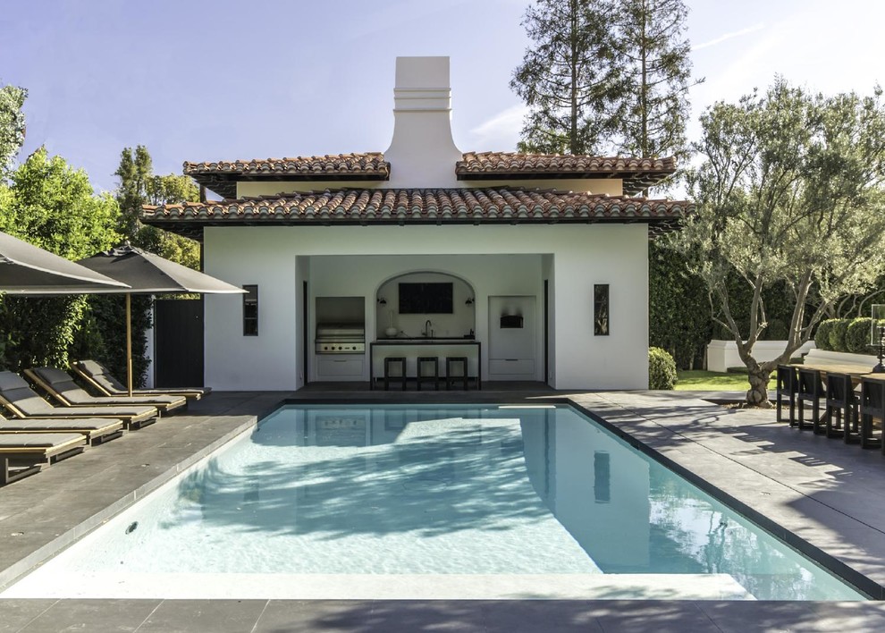 Expansive mediterranean back rectangular lengths swimming pool in Los Angeles with a pool house and stamped concrete.