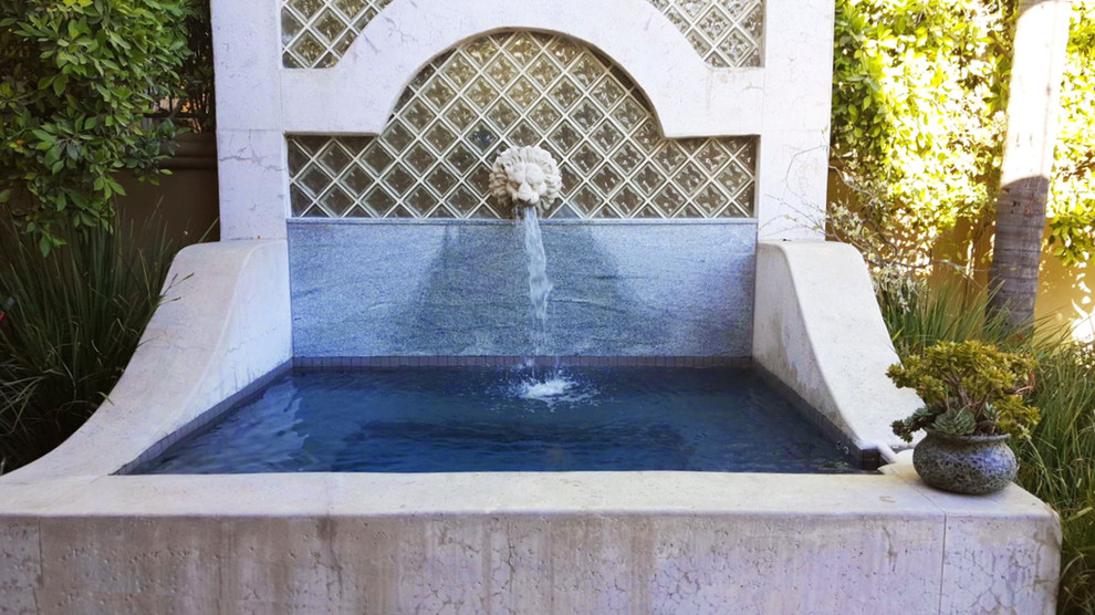 Foto de piscina con fuente alargada mediterránea grande a medida en patio trasero con adoquines de piedra natural