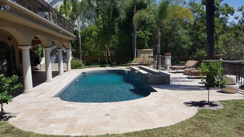 Ispirazione per una grande piscina monocorsia mediterranea personalizzata dietro casa con fontane e pavimentazioni in pietra naturale