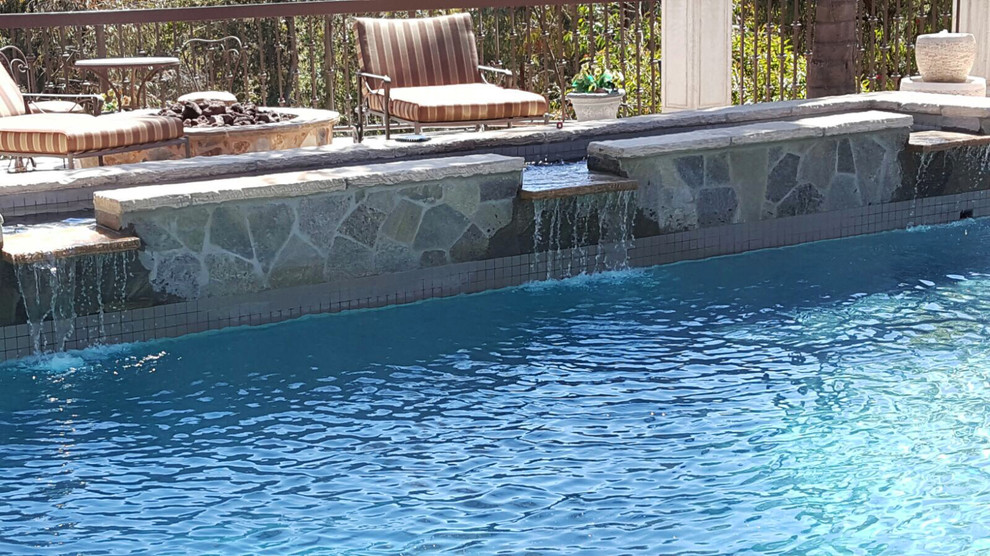 Inspiration for a large mediterranean back custom shaped lengths swimming pool in Los Angeles with a water feature and natural stone paving.