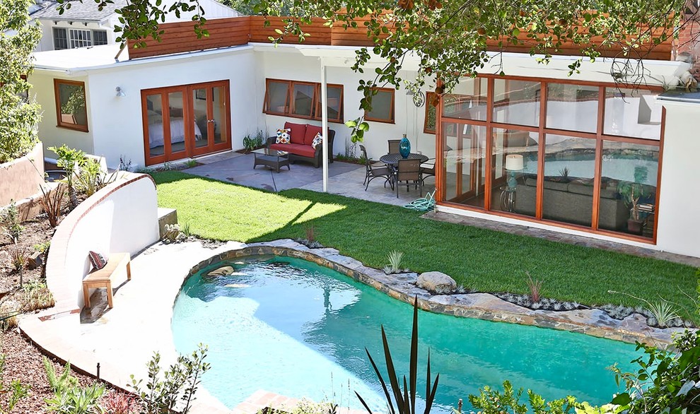 Foto de piscina alargada vintage de tamaño medio tipo riñón en patio trasero con adoquines de piedra natural
