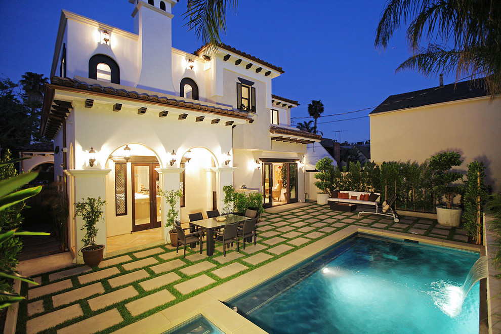 Mittelgroßer Mediterraner Pool hinter dem Haus in rechteckiger Form mit Wasserspiel und Natursteinplatten in Los Angeles