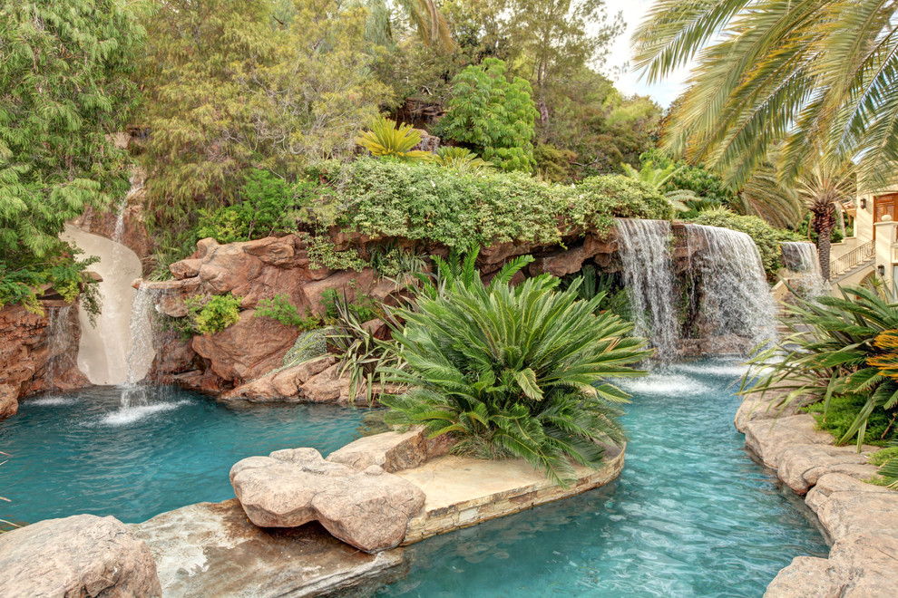 Imagen de piscina con tobogán natural exótica extra grande a medida en patio trasero con adoquines de piedra natural