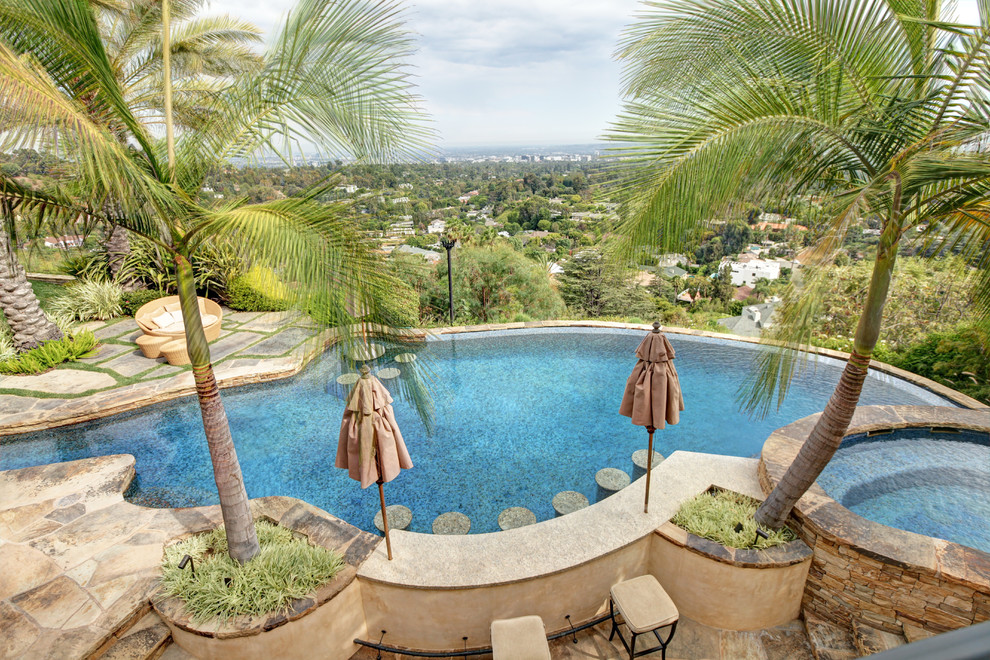 Photo of an expansive world-inspired back custom shaped natural swimming pool in Los Angeles with natural stone paving.