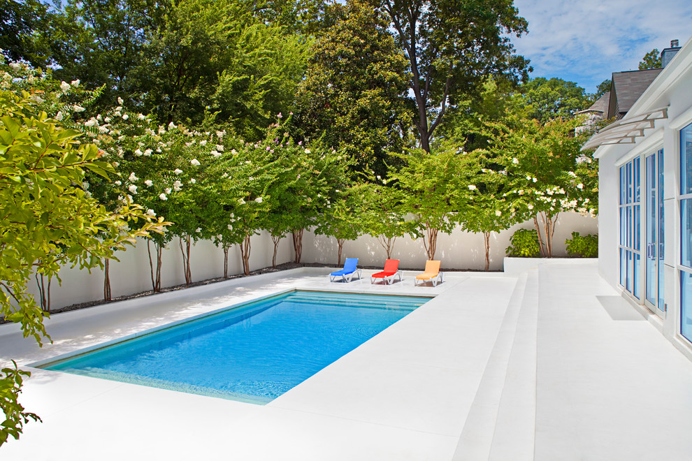 Modern inredning av en rektangulär pool, med betongplatta och poolhus