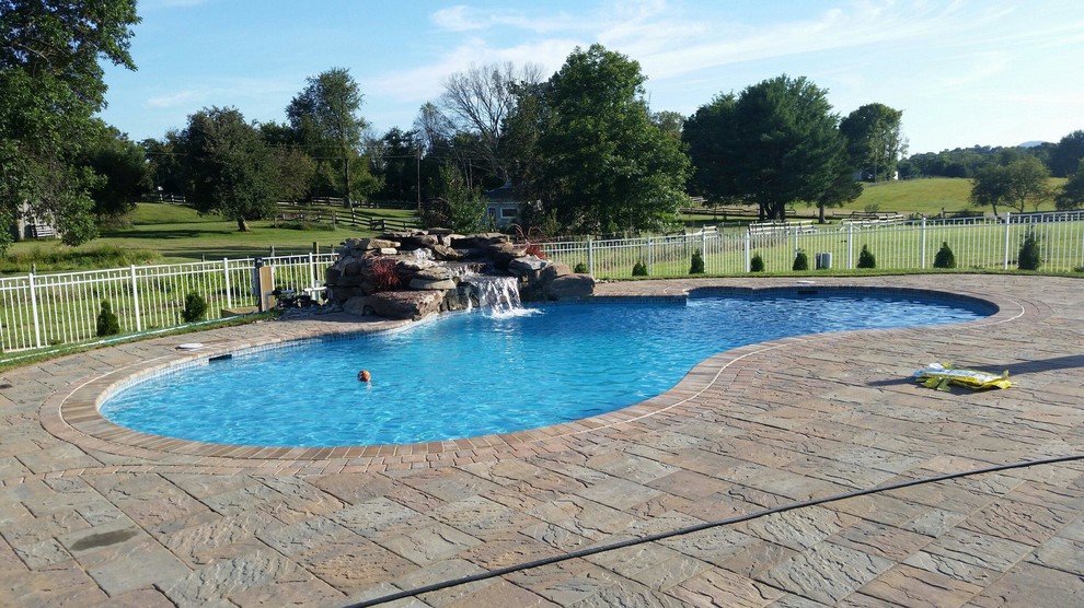 Immagine di una piscina personalizzata di medie dimensioni e dietro casa con fontane e pavimentazioni in cemento