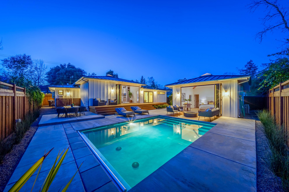 Diseño de casa de la piscina y piscina de estilo de casa de campo grande rectangular en patio trasero con losas de hormigón