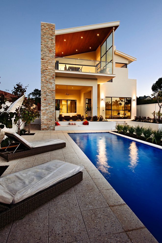 Ejemplo de piscina alargada actual grande rectangular en patio trasero con adoquines de hormigón