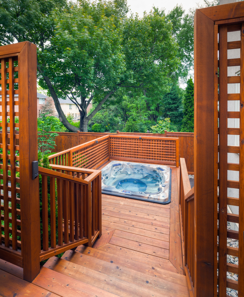 Cette photo montre une piscine arrière craftsman de taille moyenne et sur mesure avec un bain bouillonnant et une terrasse en bois.