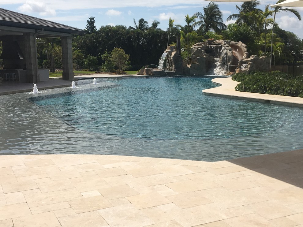 На фото: огромный естественный бассейн произвольной формы на заднем дворе в стиле кантри с водной горкой и покрытием из каменной брусчатки с