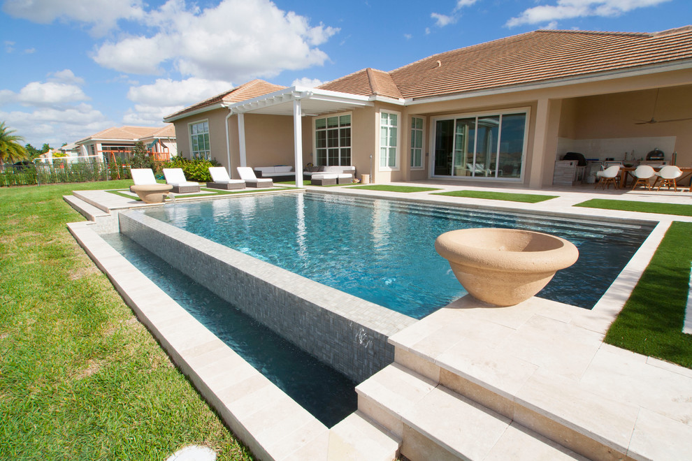 Idee per una grande piscina a sfioro infinito minimalista rettangolare dietro casa con pavimentazioni in pietra naturale