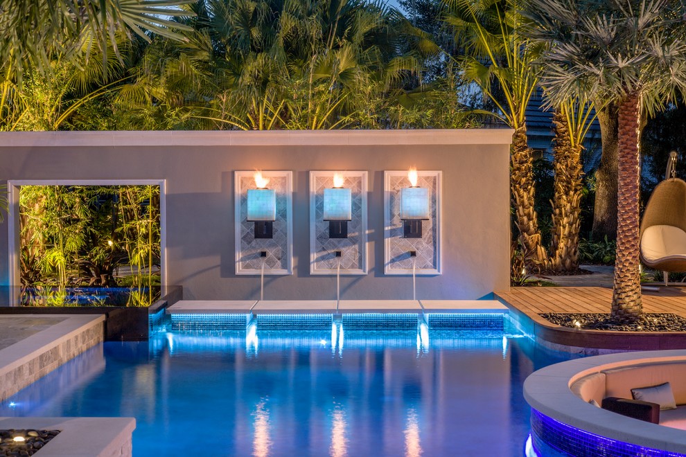 На фото: большой прямоугольный бассейн на заднем дворе в стиле модернизм с фонтаном и покрытием из каменной брусчатки с