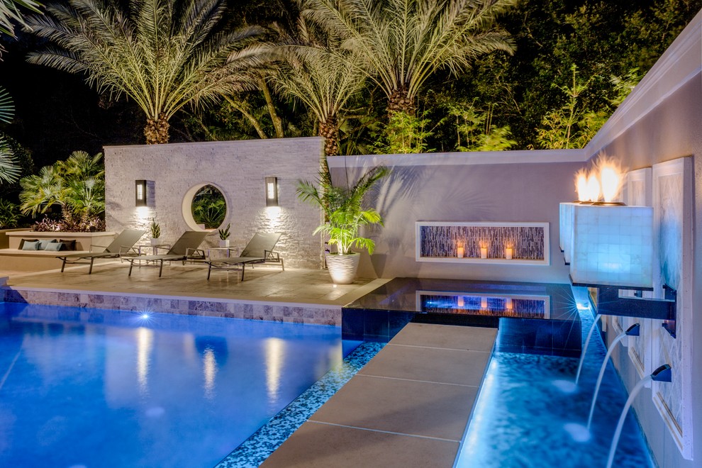 Inspiration for a large modern back custom shaped swimming pool in Tampa with a water feature and natural stone paving.