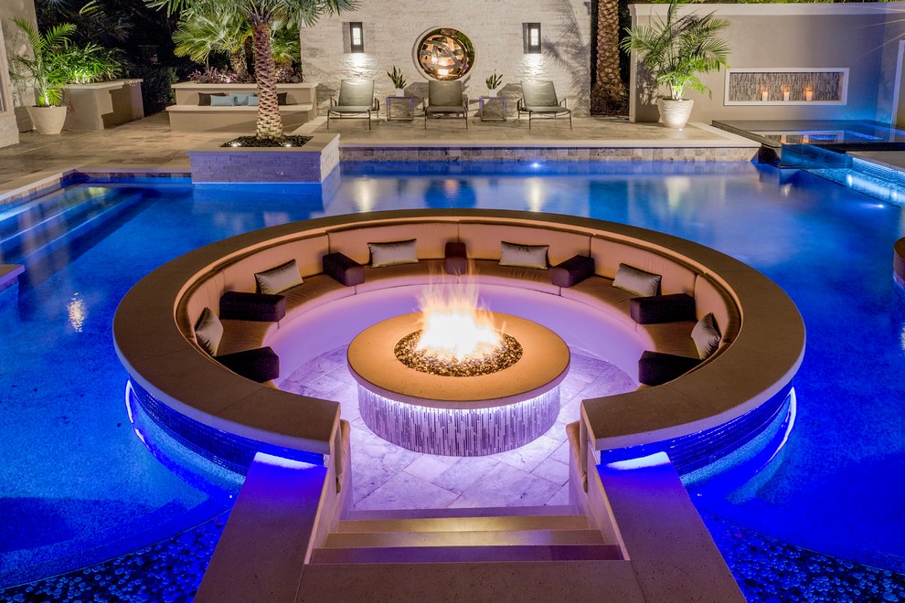 Immagine di una grande piscina moderna personalizzata dietro casa con fontane e pavimentazioni in pietra naturale