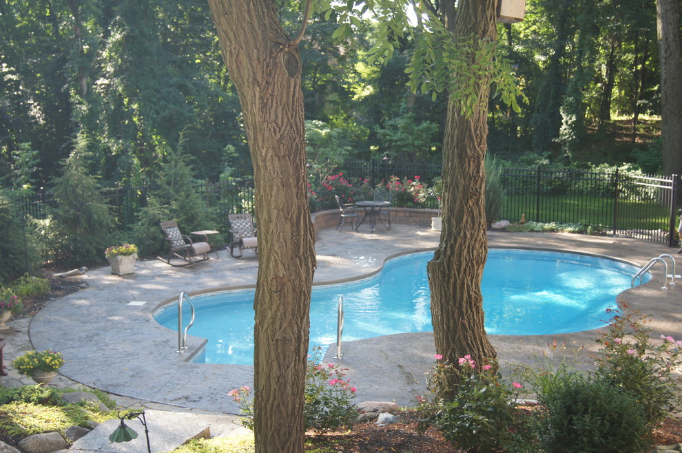 Ejemplo de piscina elevada de estilo americano de tamaño medio a medida en patio con suelo de hormigón estampado
