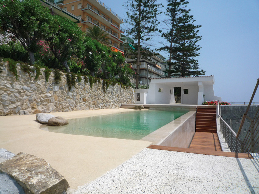Foto di una piscina naturale stile marino personalizzata di medie dimensioni e dietro casa con una dépendance a bordo piscina e lastre di cemento