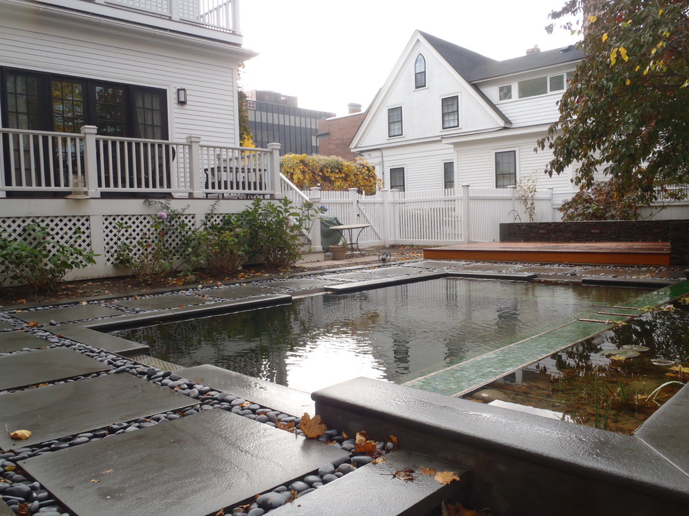 Kleiner Schwimmteich hinter dem Haus in rechteckiger Form mit Natursteinplatten in Boston