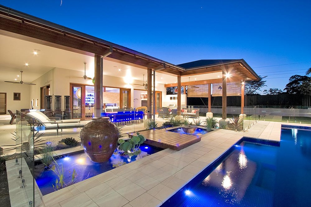 Ejemplo de casa de la piscina y piscina alargada marinera extra grande a medida en patio trasero con adoquines de piedra natural