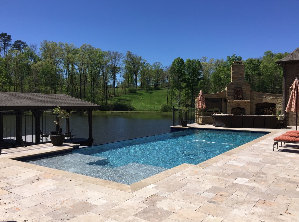 Cette photo montre une piscine à débordement et arrière rectangle avec des pavés en pierre naturelle.