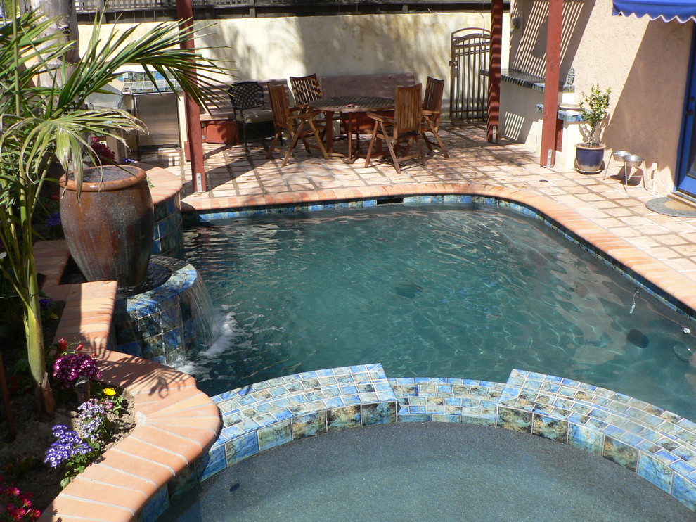 Small tuscan backyard concrete paver and custom-shaped lap hot tub photo in Orange County