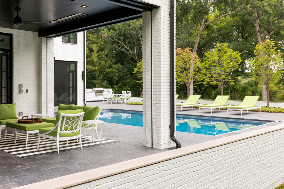 Foto di un'ampia piscina minimalista rettangolare dietro casa con pavimentazioni in pietra naturale