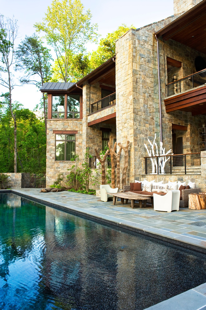 Ispirazione per una piscina a sfioro infinito stile rurale rettangolare con pavimentazioni in pietra naturale