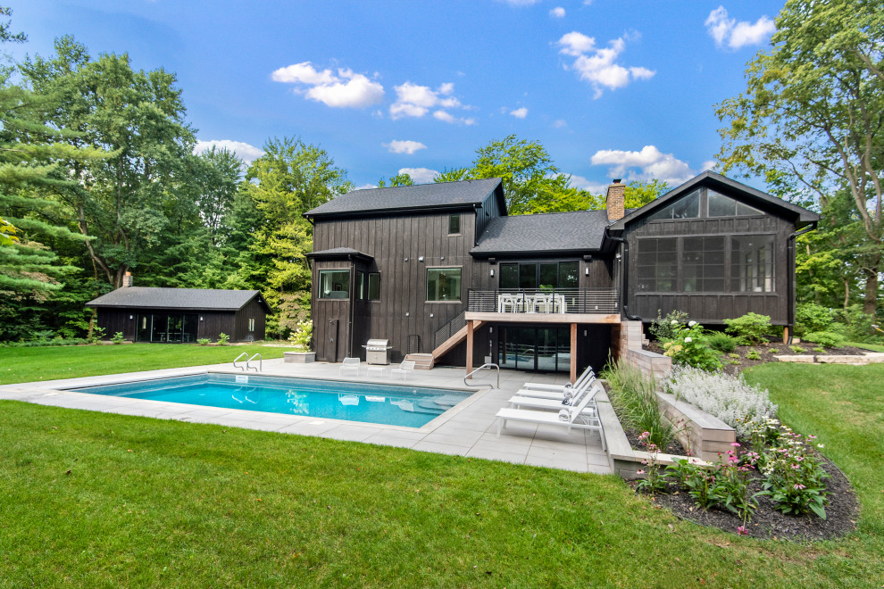 Moderner Pool hinter dem Haus in rechteckiger Form mit Natursteinplatten