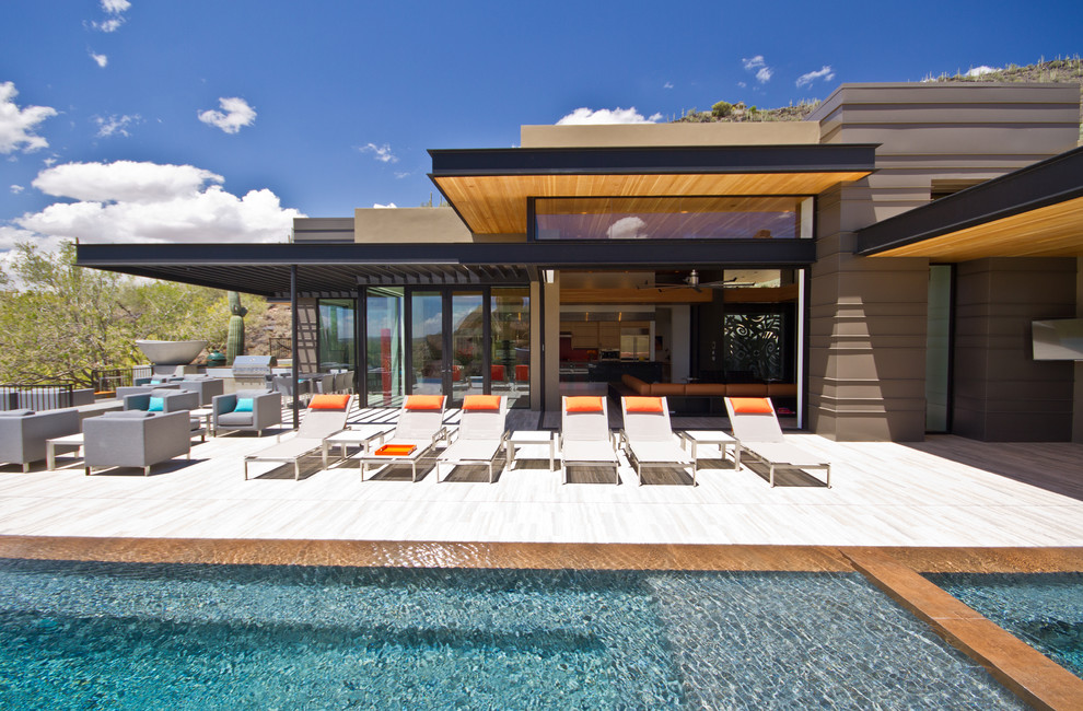 Example of a trendy backyard tile and rectangular infinity pool fountain design in Phoenix