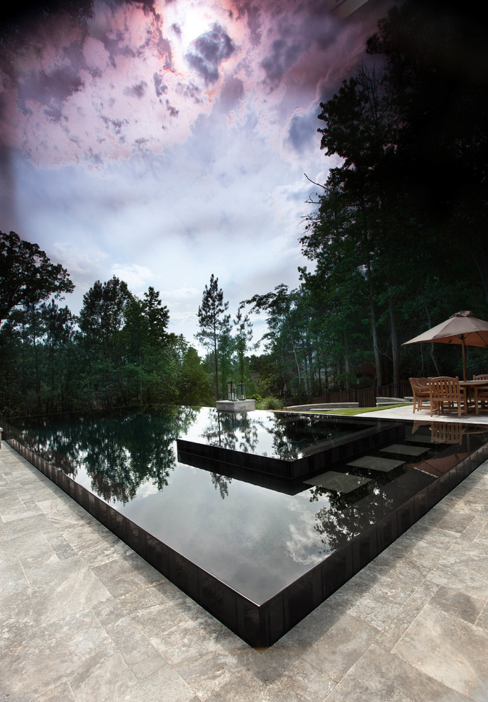Aménagement d'une grande piscine à débordement et arrière moderne rectangle avec un bain bouillonnant et des pavés en pierre naturelle.