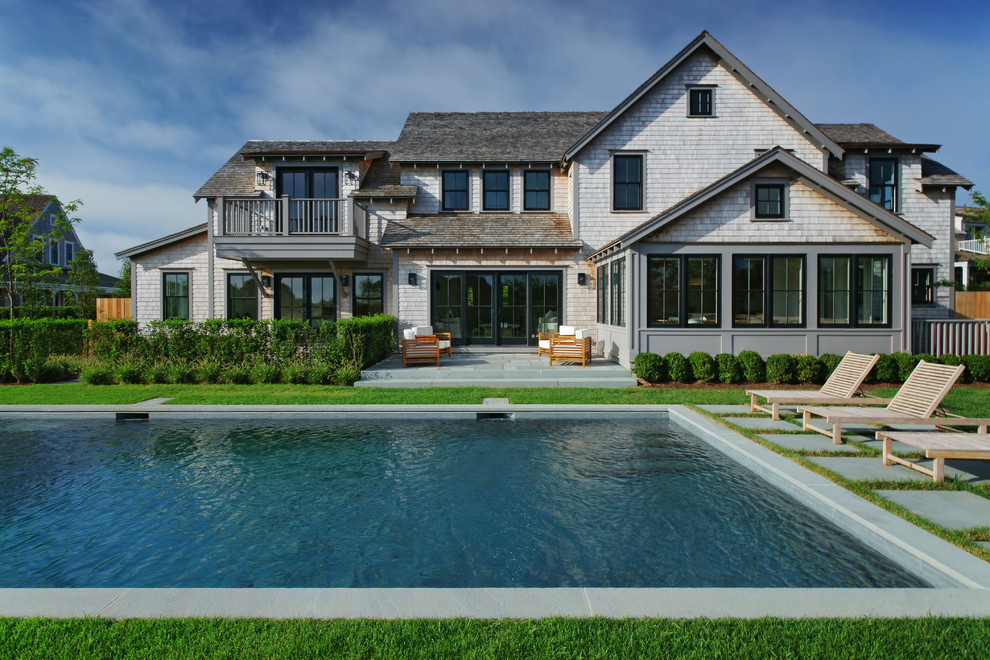 Diseño de piscina de estilo de casa de campo grande rectangular en patio trasero con adoquines de piedra natural