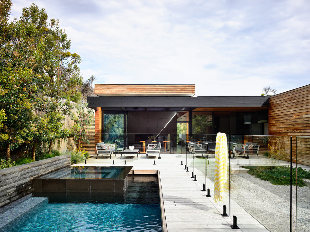 Esempio di una piscina minimal rettangolare di medie dimensioni e dietro casa con una vasca idromassaggio e pedane