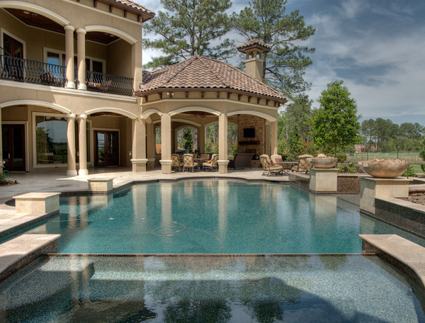 Idee per un'ampia piscina a sfioro infinito classica personalizzata dietro casa con pavimentazioni in pietra naturale