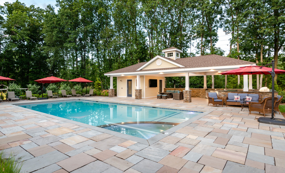 Immagine di una grande piscina costiera rettangolare dietro casa con una dépendance a bordo piscina e pavimentazioni in pietra naturale