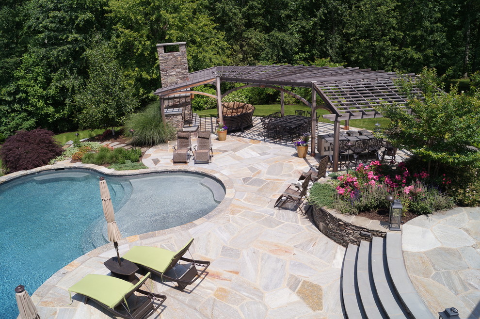 Idee per una grande piscina chic personalizzata dietro casa con pavimentazioni in pietra naturale