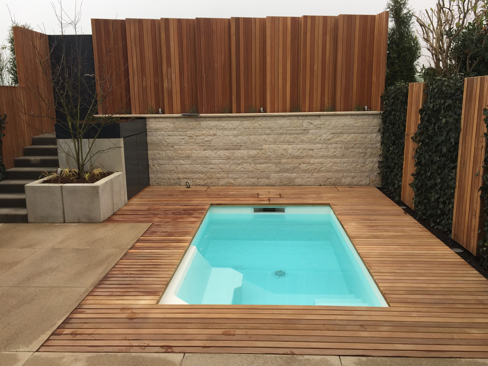 Diseño de piscina actual pequeña rectangular en patio trasero con entablado