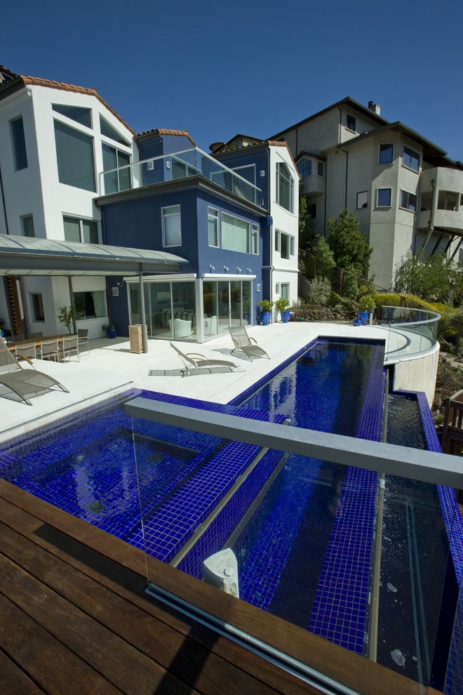 Foto di una piscina a sfioro infinito contemporanea rettangolare di medie dimensioni e dietro casa con una vasca idromassaggio e pavimentazioni in pietra naturale