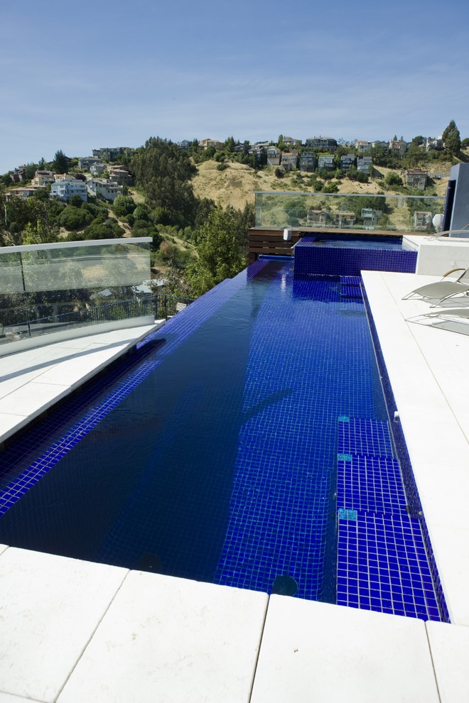 Esempio di una grande piscina a sfioro infinito contemporanea rettangolare dietro casa con fontane e piastrelle