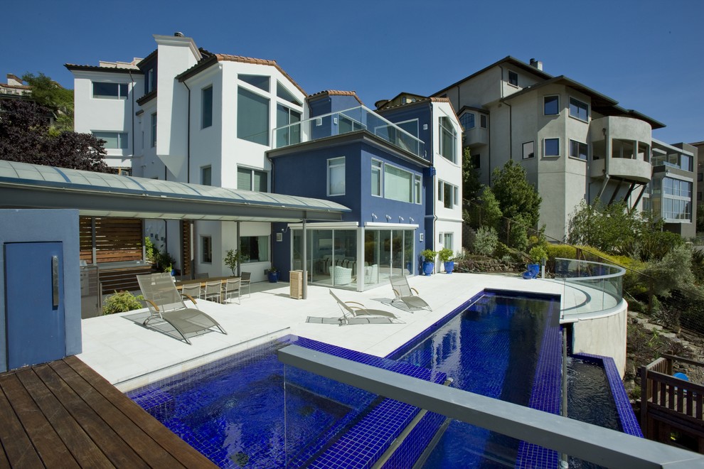 Ejemplo de piscina con fuente infinita contemporánea grande rectangular en patio trasero con suelo de baldosas