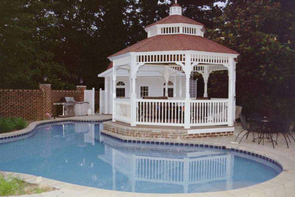 This is an example of a classic courtyard custom shaped swimming pool in DC Metro with a pool house and concrete paving.